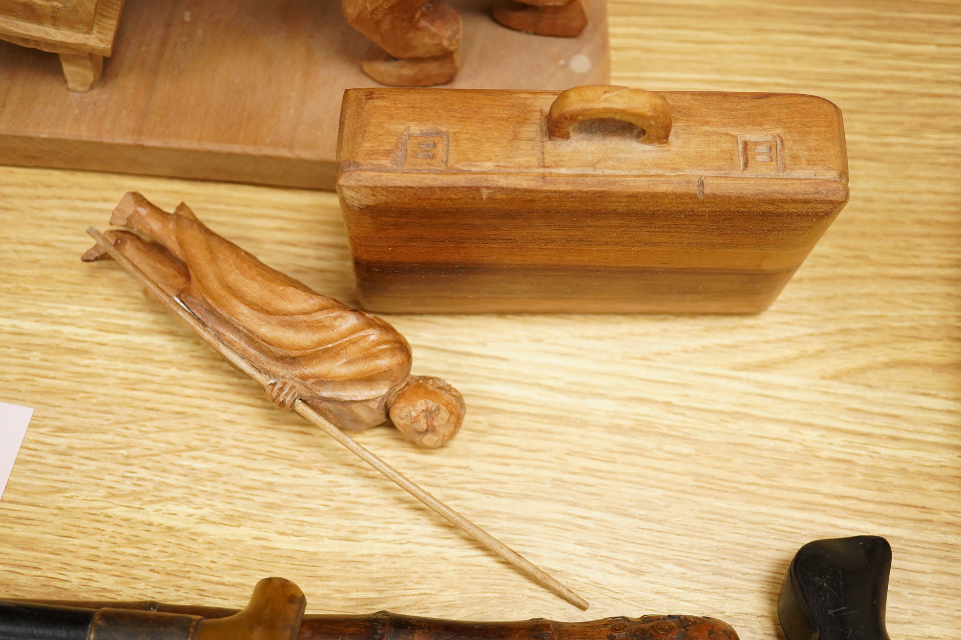 Pierre Decorse (b.1953), a naturalistically modelled wooden sculpture of a grandfather clock and a figure, together with two other sculptures comprising a suitcase and figure, largest 42cm high